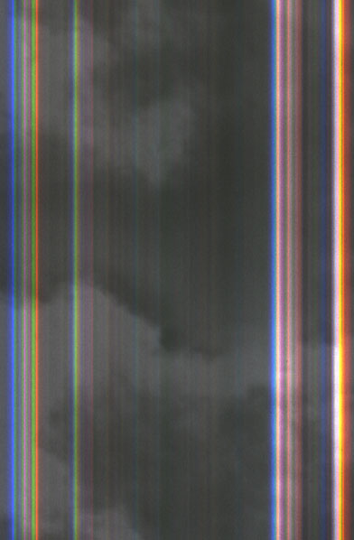 Ein schwarzweiß fotografierter Wolkenhimmel mit vertikal darüber laufenden Farbstreifen, die ein Scannerfehler verursachte.
